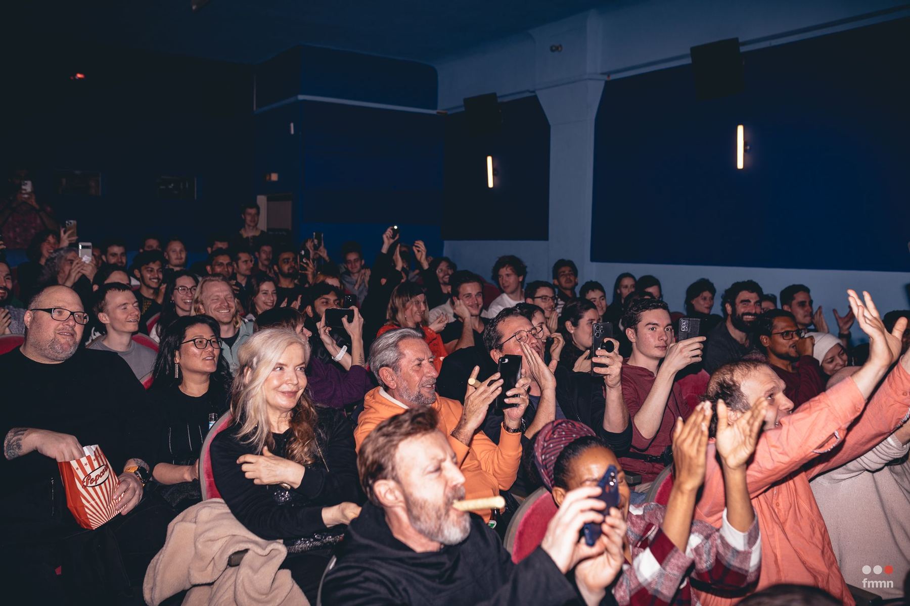 A packed Movie Sprint audience reacting during a screening, hands in the air